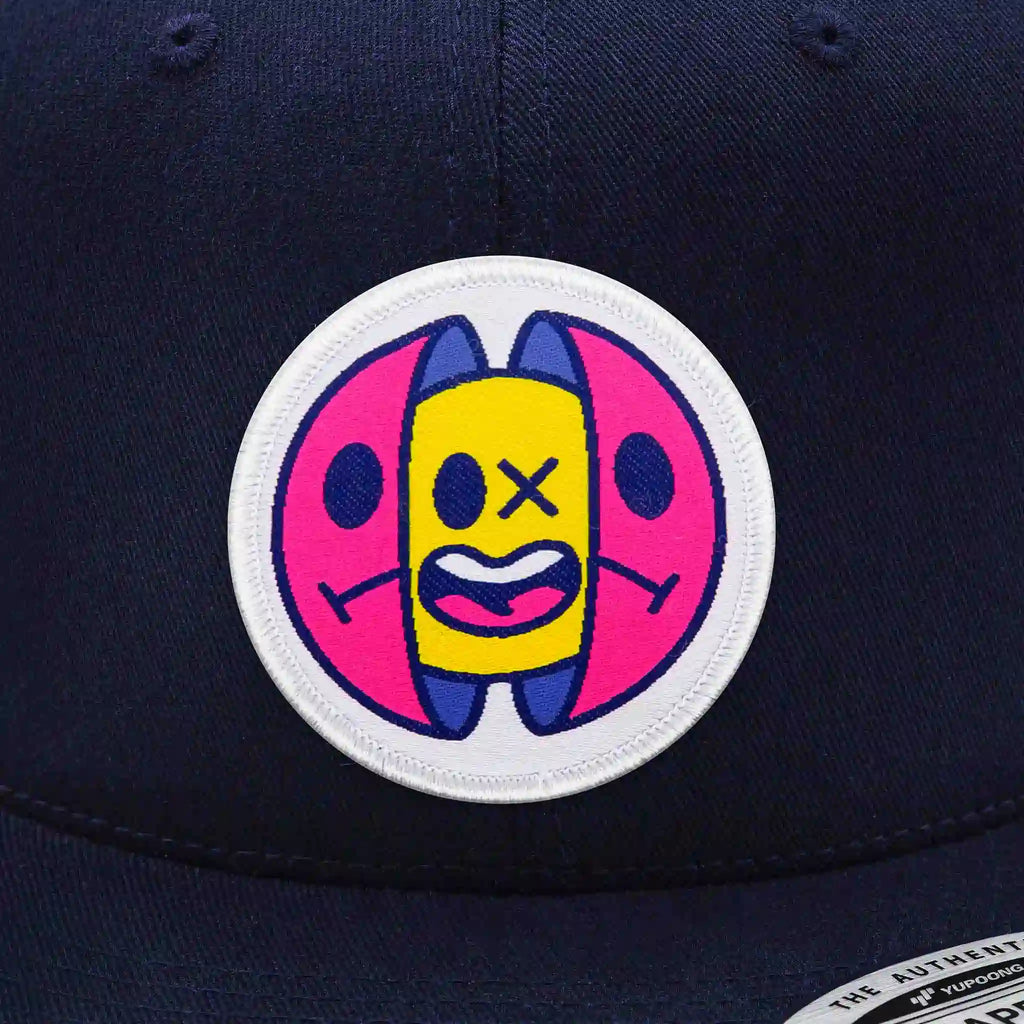 Casquette Flexfit navy avec écusson capsule pop art rose, jaune et bleu, snapback ajustable et tendance streetwear.