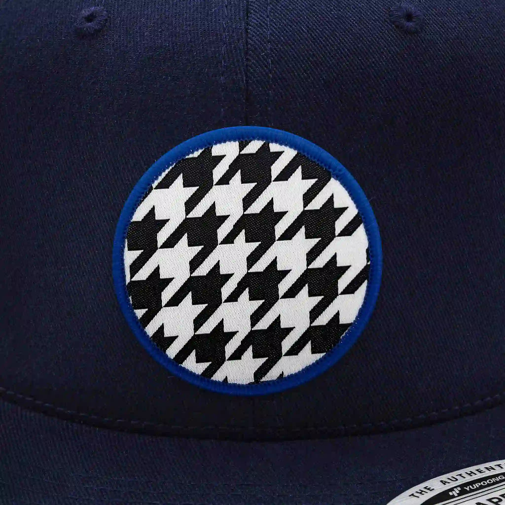 Casquette Flexfit bleue navy snapback avec écusson rond noir et blanc motif pied-de-poule classique, modèle tendance personnalisable avec velcro et écussons interchangeables.