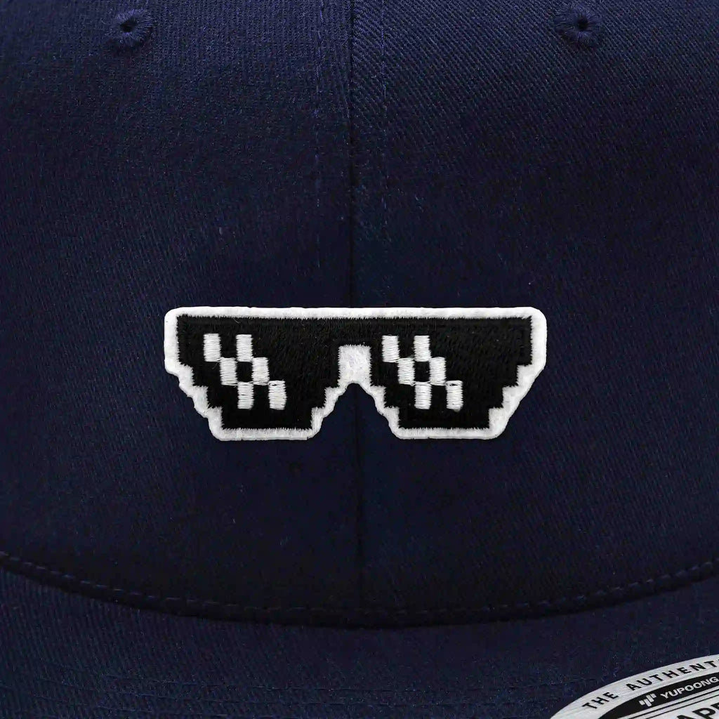 Casquette Flexfit bleue navy snapback avec écusson brodé lunettes pixel noires et blanches style Thug Life, modèle urbain personnalisable avec velcro et écussons interchangeables.
