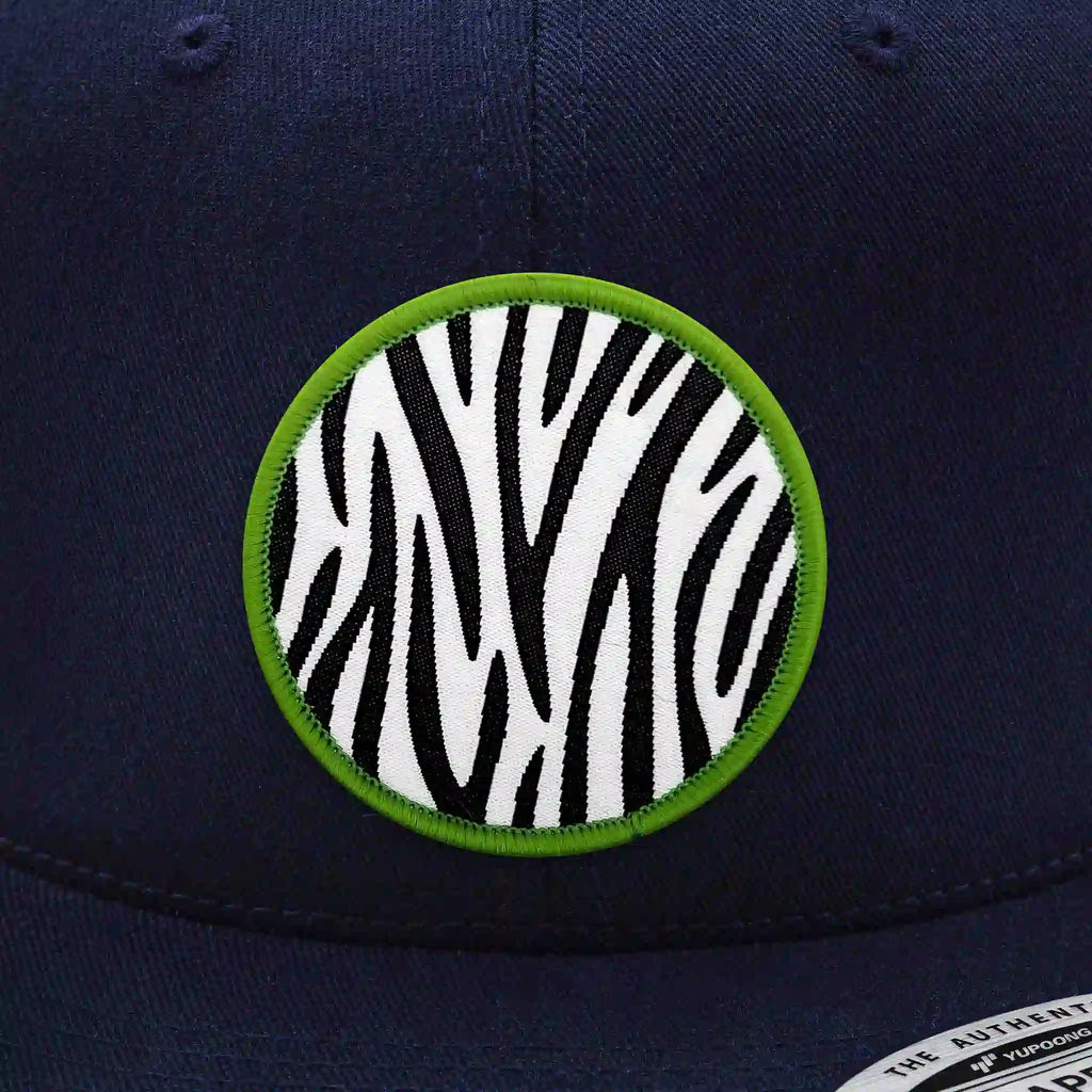 Casquette Flexfit bleue navy snapback avec écusson rond velcro motif zèbre noir et blanc bordé de vert, modèle urbain personnalisable avec écussons interchangeables
