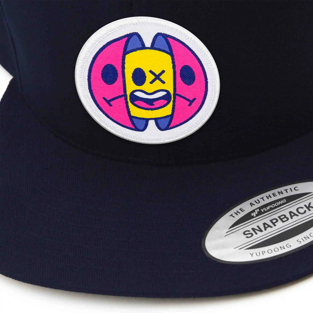 Casquette Flexfit bleue marine snapback avec écusson rond velcro représentant un design capsule pop art jaune, rose et bleu, modèle personnalisable avec écussons interchangeables.
