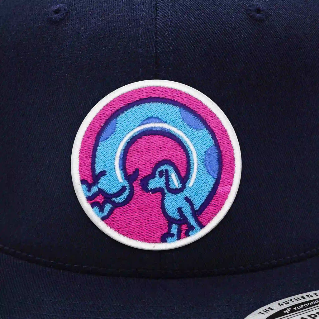 Casquette Flexfit bleu navy snapback avec écusson rond velcro représentant deux chiens-saucisses bleus formant un arc, modèle original personnalisable avec écussons interchangeables.