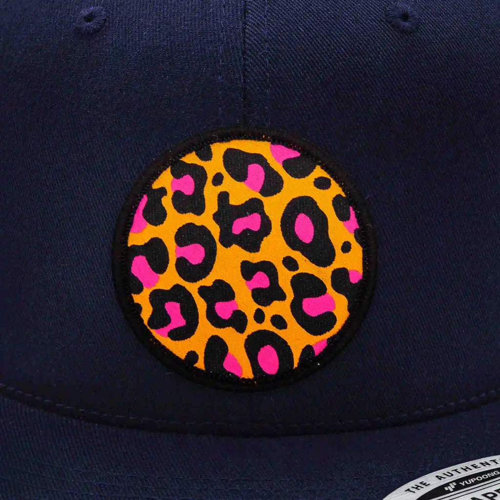 Casquette flexfit
 bleue marine snapback avec écusson rond imprimé motif léopard orange, noir et rose, modèle streetwear personnalisable avec velcro et écussons interchangeables.