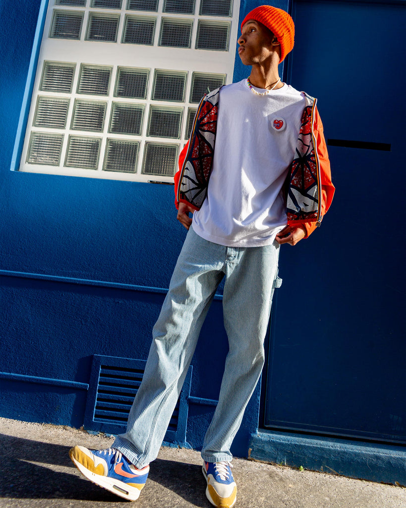 Homme debout en extérieur, portant un t-shirt avec un écusson thermocollant cœur, patch scratch au design vibrant