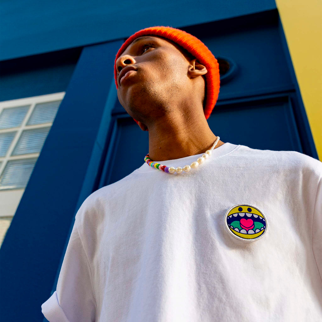 Portrait stylisé d’un modèle portant un t-shirt blanc avec écusson smiley sur la poitrine.