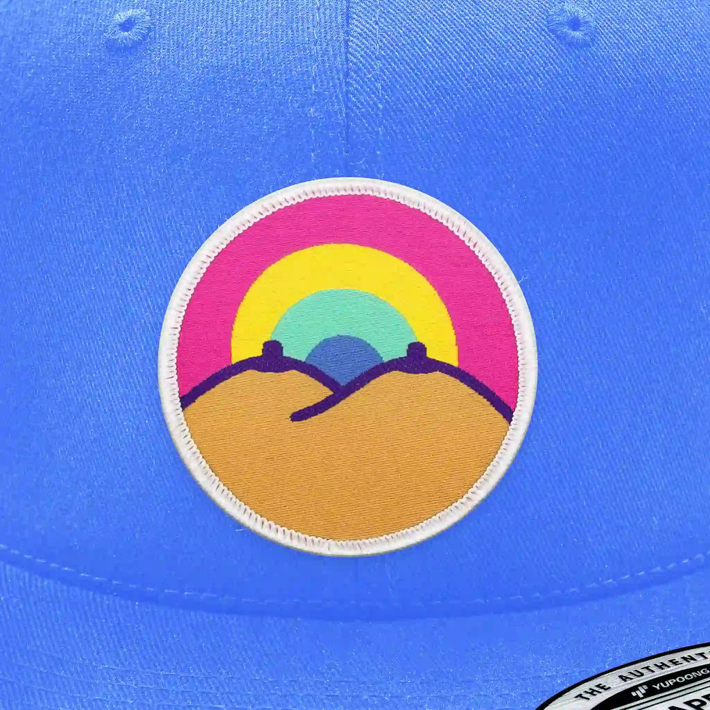 Casquette bleu clair avec écusson thermocollant arc-en-ciel au-dessus de collines.