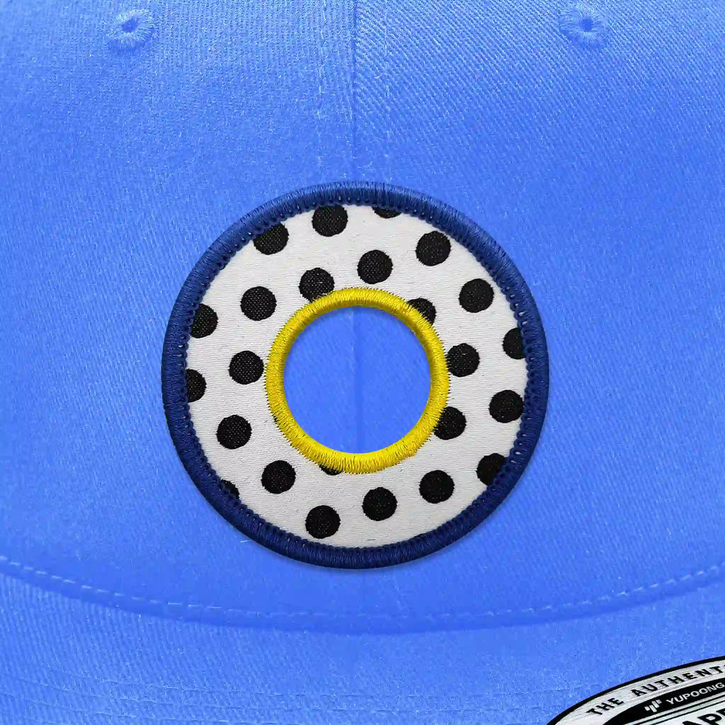 Casquette bleu clair avec écusson thermocollant motif géométrique style Memphis noir et blanc.