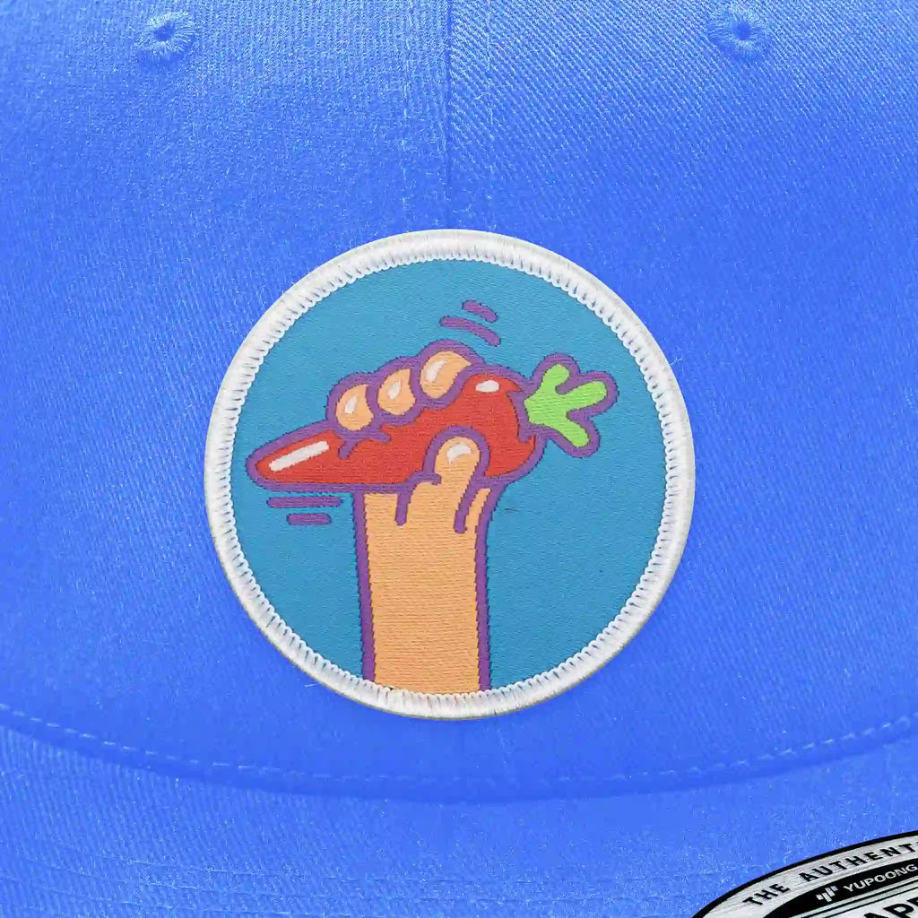 Casquette bleu clair avec écusson thermocollant représentant une main tenant une carotte orange, modèle streetwear original.