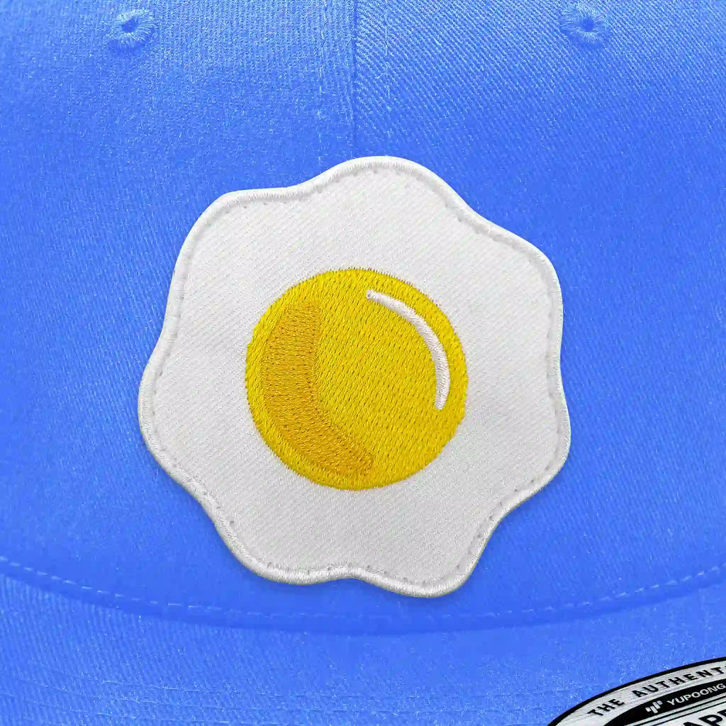 Casquette bleu clair avec écusson thermocollant en forme d’œuf au plat.