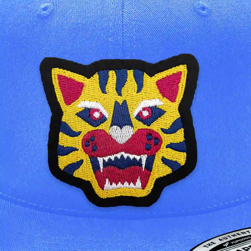Casquette bleu clair avec écusson thermocollant tête de tigre jaune et rouge.