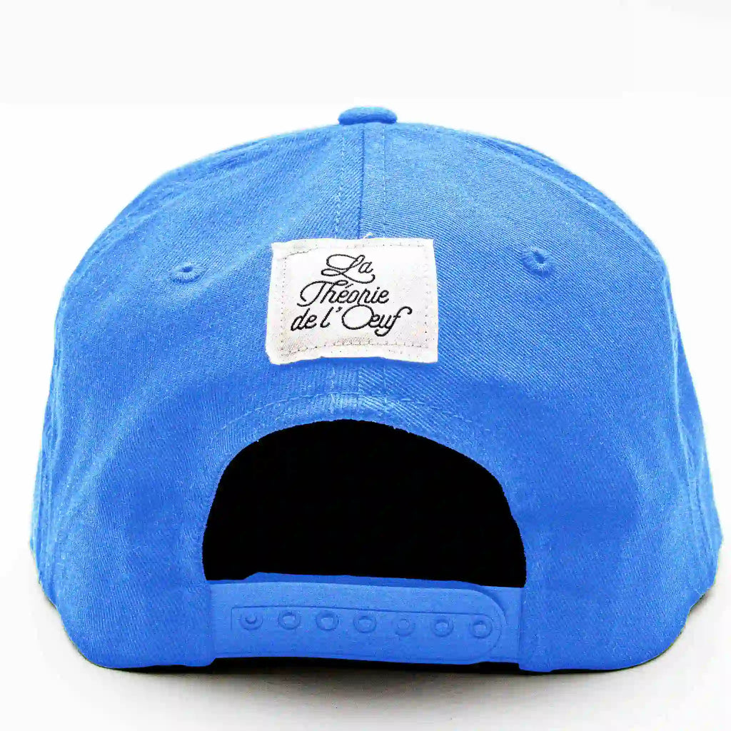 Vue arrière casquette Flexfit bleu clair avec étiquette brodée « La Théorie de l’Œuf », snapback ajustable.
