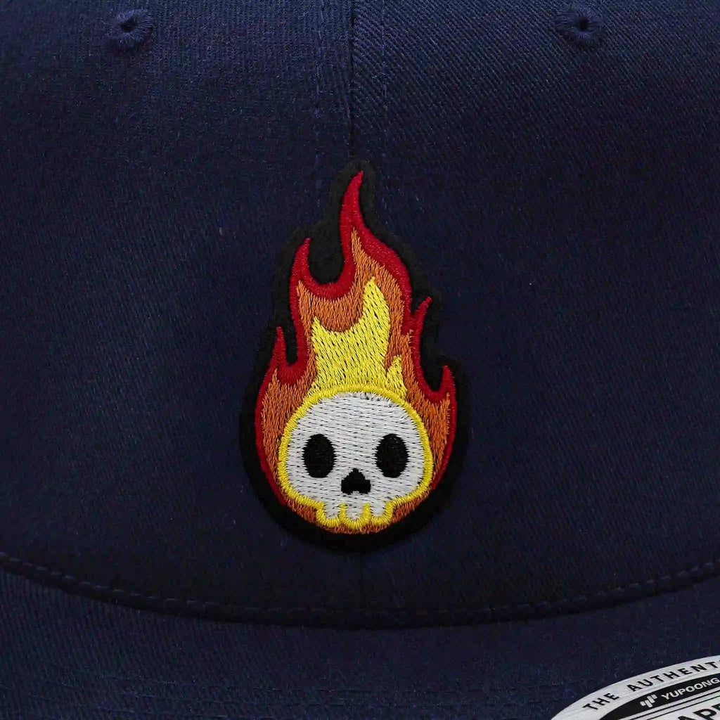 Casquette Flexfit bleue navy snapback avec écusson brodé représentant un crâne blanc en flammes rouges et jaunes, modèle streetwear personnalisable avec velcro et écussons interchangeables.Casquette Flexfit navy avec écusson tigre rugissant brodé, style urbain et tendance, snapback ajustable.