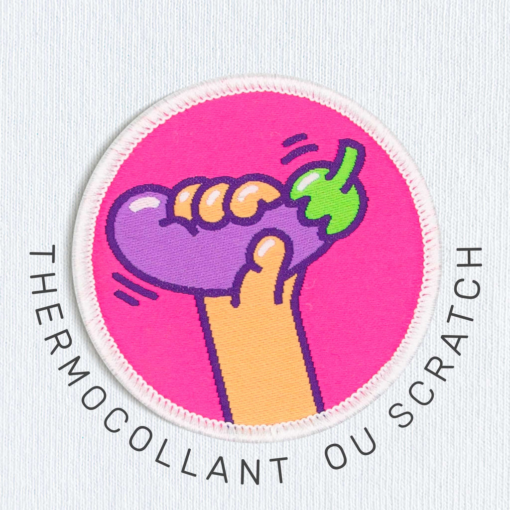 Gros plan d’un patch aubergine sur tissu clair, avec options thermocollant ou scratch visibles.