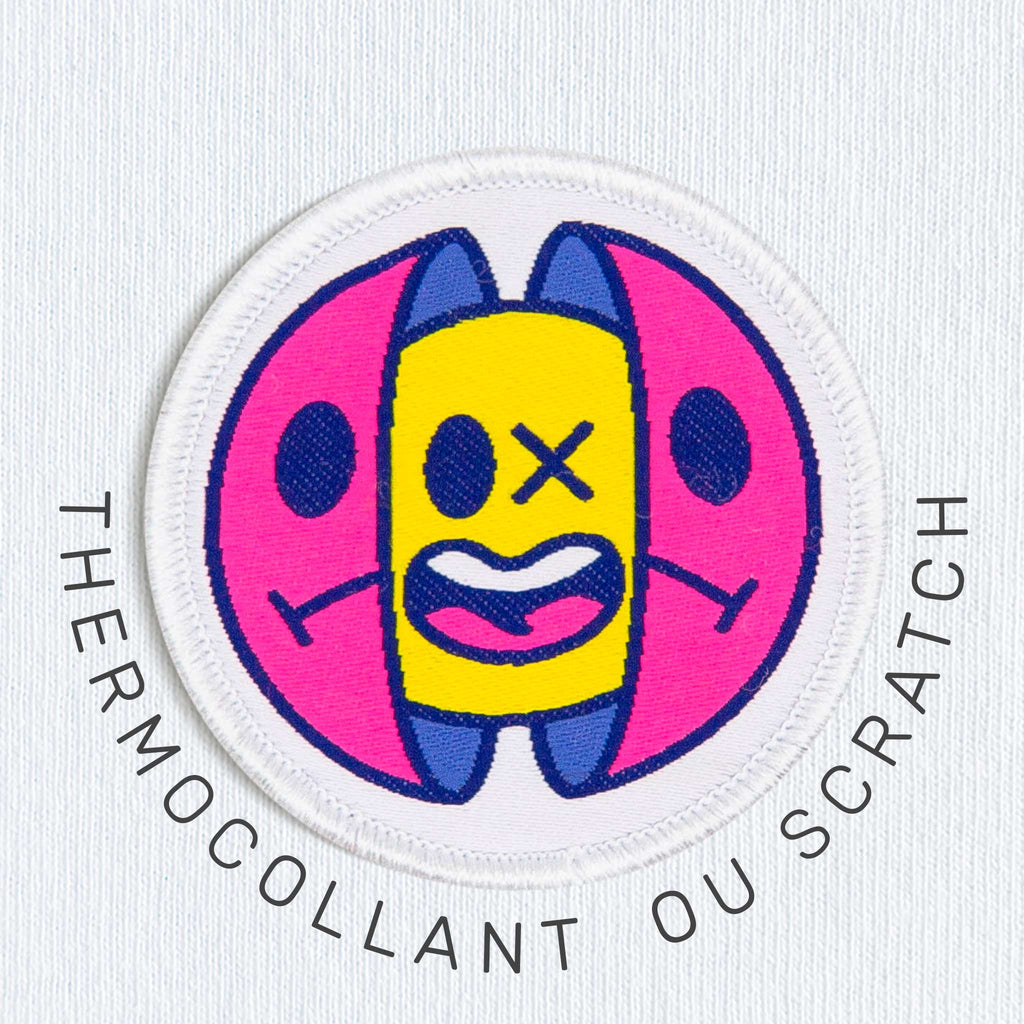 Écusson thermocollant ou scratch coloré en forme de capsule stylisée, brodé sur fond blanc – accessoire textile personnalisé