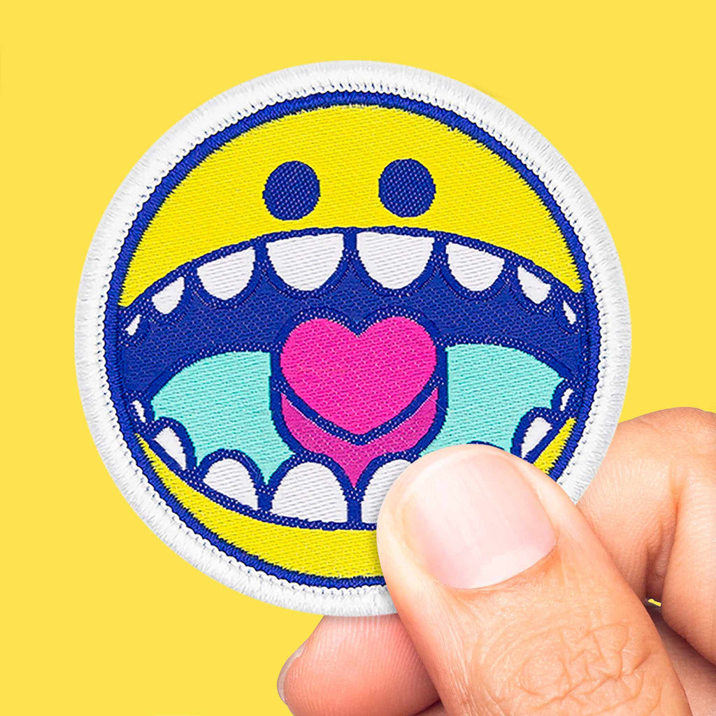 Gros plan sur un écusson brodé représentant un smiley jaune avec détails bleu