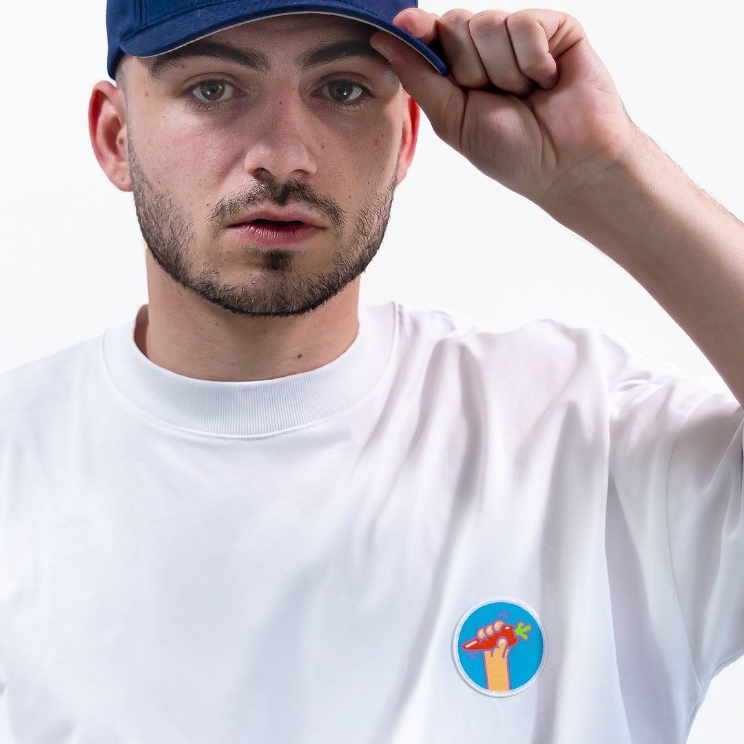 Homme avec une casquette portant un super t-shirt en coton bio avec un écusson carotte positionné sur le cœur